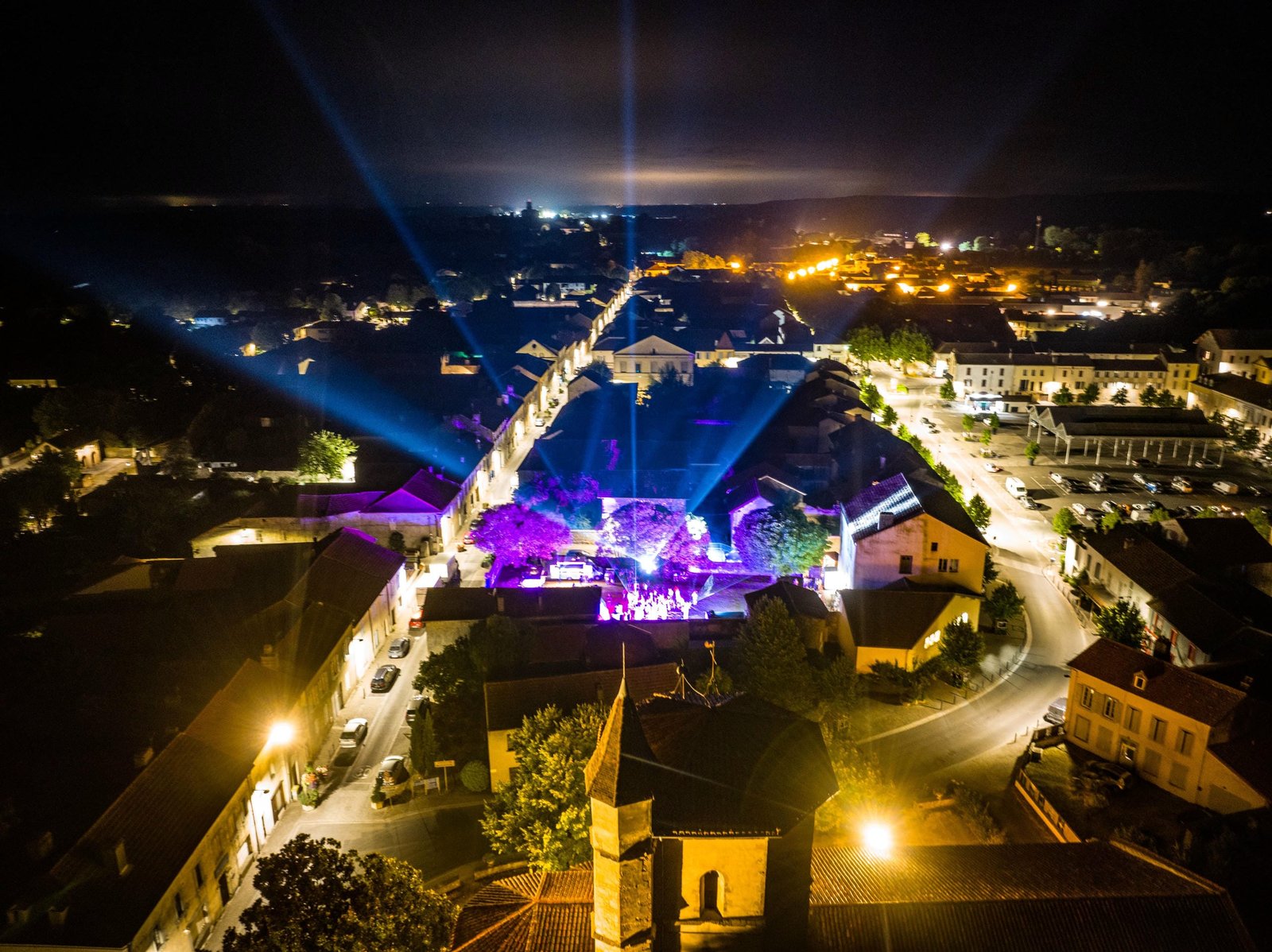 Vue aérienne de nuit — faisceau lumineux au-dessus du village